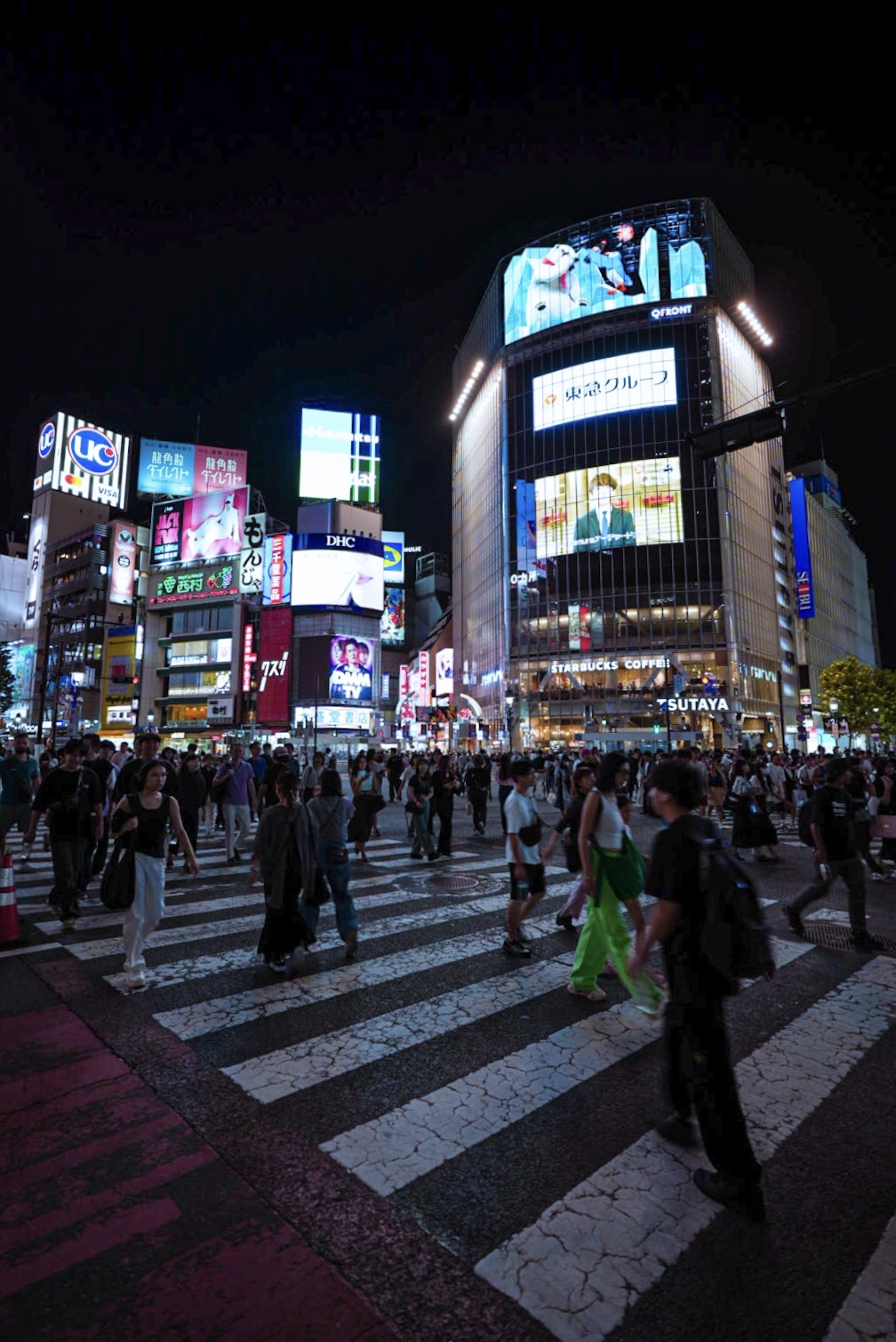 Busy Shibuya crossing in Tokyo with neon lights and crowds